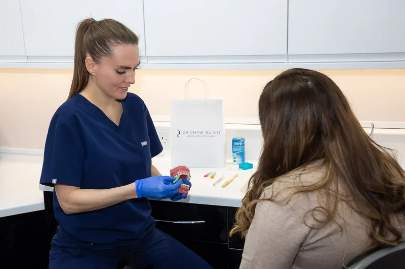 A hygienist showing a patient how to brush effectively, using a dental model, at our Hammersmith studio