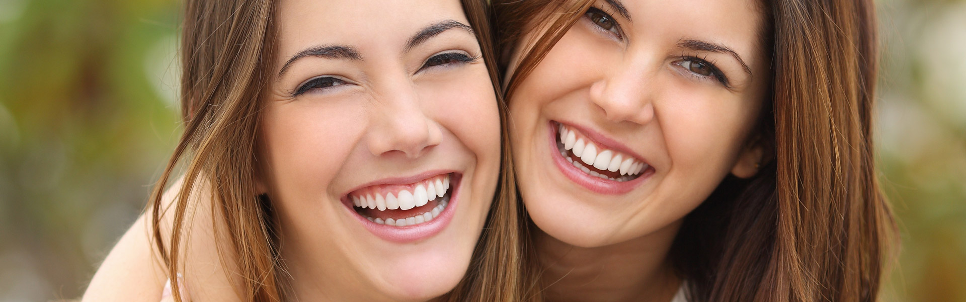 Two women friends smiling with straight, white teeth after teeth straightening treatment